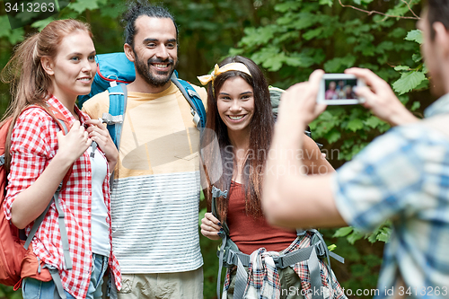 Image of friends with backpack photographing by smartphone