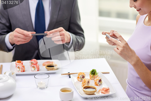 Image of close up of couple with smartphones at restaurant