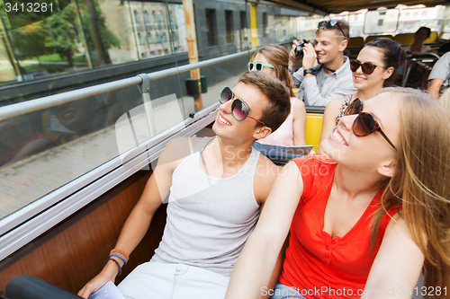 Image of group of smiling friends traveling by tour bus