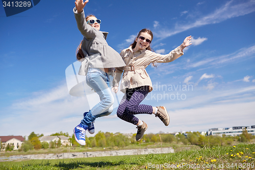 Image of happy little girls jumping high outdoors