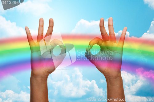 Image of hands showing ok sign over rainbow background