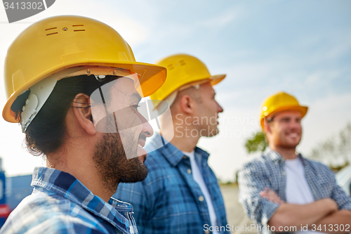 Image of group of smiling builders in hardhats outdoors