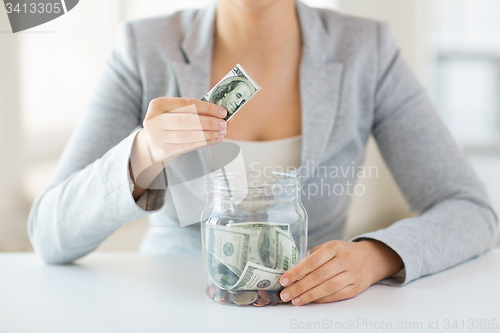 Image of close up of woman hands and dollar money in jar