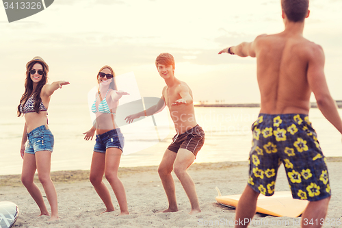 Image of smiling friends in sunglasses with surfs on beach