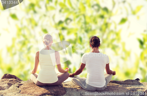 Image of smiling couple making yoga exercises outdoors