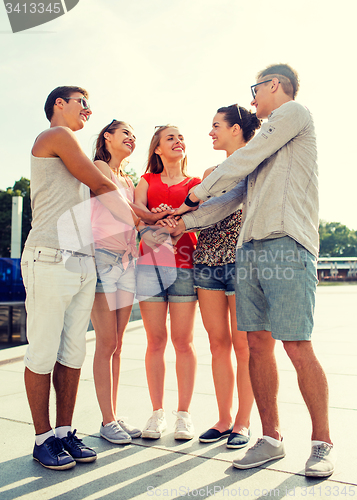 Image of group of smiling friends with hands on top in city