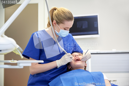 Image of female dentist checking patient girl teeth