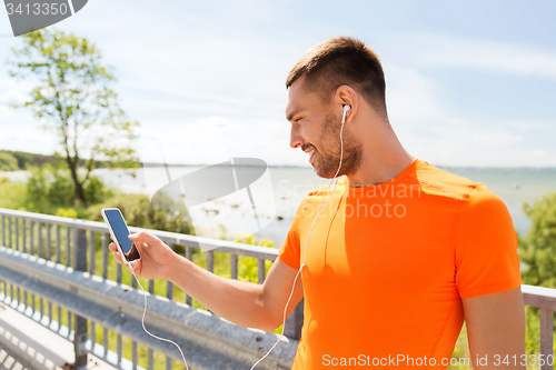 Image of smiling young man with smartphone and earphones