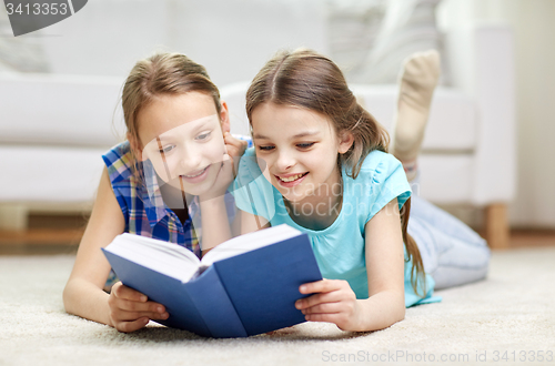 Image of two happy girls reading book at home