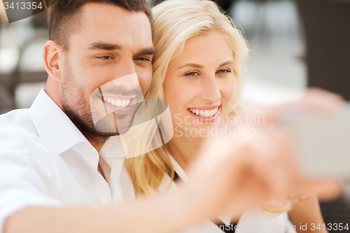 Image of happy couple taking selfie with smatphone outdoors