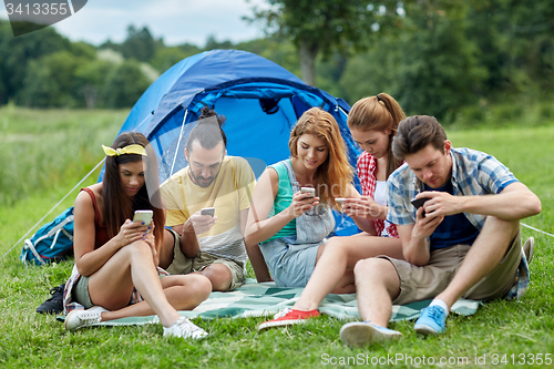 Image of friends with smartphone and tent at camping
