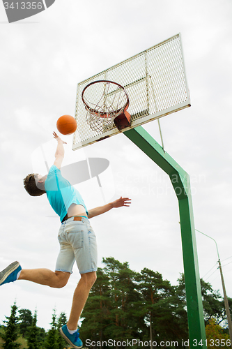 Image of young man playing basketball outdoors