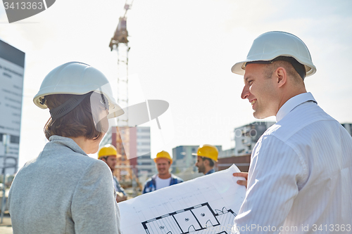 Image of happy architects with blueprint at building