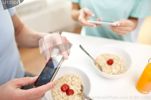 Image of close up of couple with smartphones at breakfast