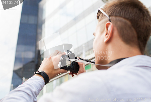 Image of close up of young man with digital camera in city