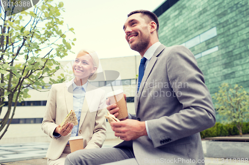 Image of smiling businessmen with paper cups outdoors