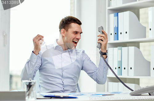 Image of furious businessman calling on phone in office