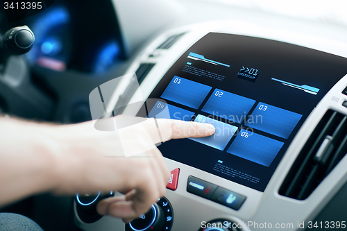 Image of hand pushing button on car control panel screen