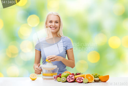 Image of smiling woman squeezing fruit juice