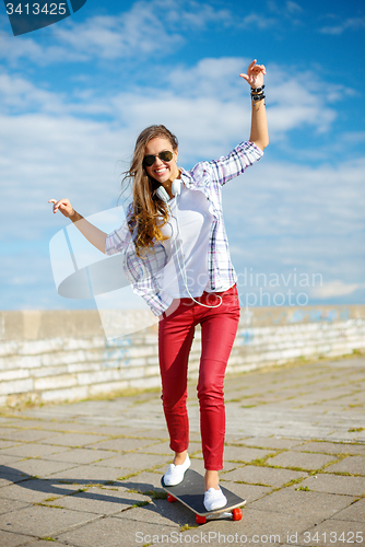 Image of smiling teenage girl riding skate outside