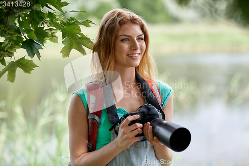 Image of happy woman with backpack and camera outdoors