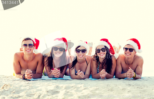 Image of group of friends in santa helper hats on beach