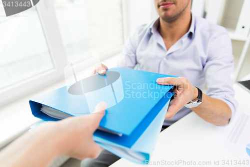 Image of close up of businessman taking folders from hand