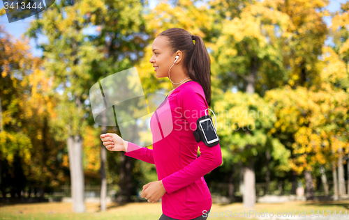 Image of girl with smartphone and earphones running at park