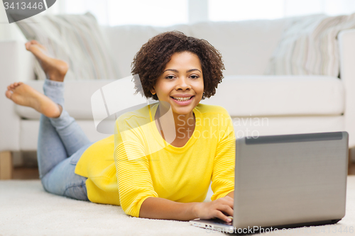 Image of happy african american woman with laptop at home