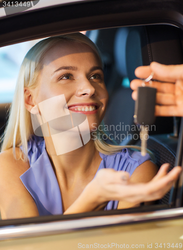 Image of happy woman getting car key in auto show or salon