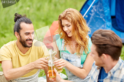 Image of happy friends with tent and drinks at campsite