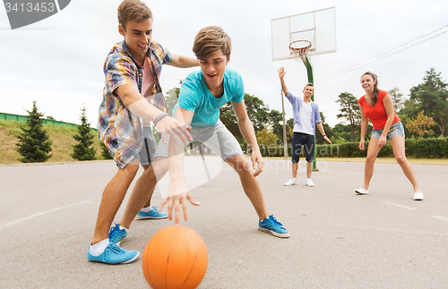 Image of group of happy teenagers playing basketball