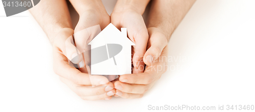 Image of man and woman hands with white paper house