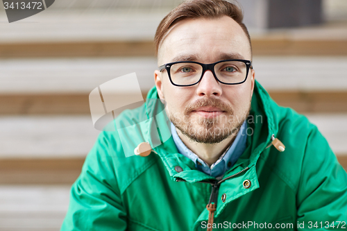 Image of happy young hipster man sitting on stairs in city