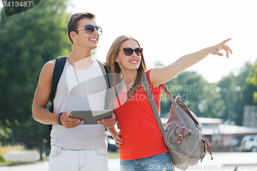 Image of smiling couple with tablet pc and backpack in city