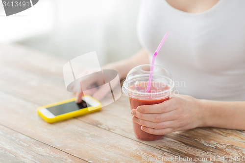 Image of close up of woman with smartphone and smoothie