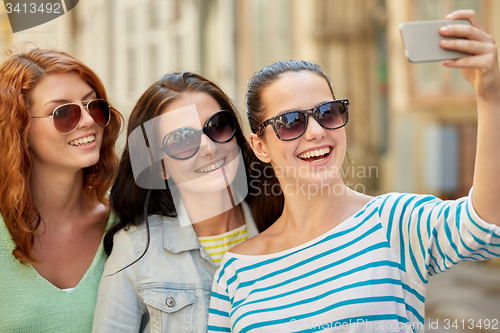 Image of smiling young women taking selfie with smartphone