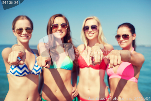 Image of group of happy women pointing at you on beach