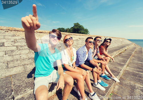 Image of group of smiling friends sitting on city street