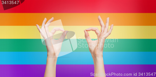 Image of hands showing ok sign over rainbow background