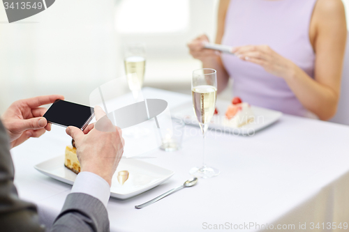 Image of close up of couple with smartphones at restaurant