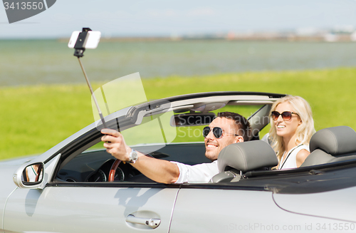 Image of happy couple in car taking selfie with smartphone