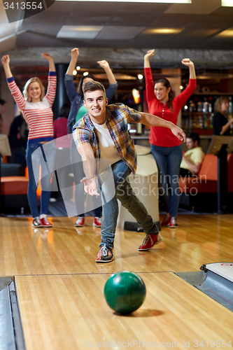 Image of happy young man throwing ball in bowling club