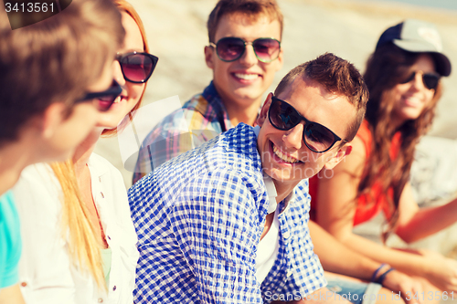 Image of close up of smiling friends sitting on city street