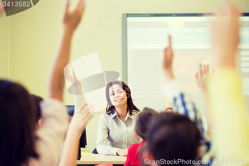 Image of group of school kids raising hands in classroom