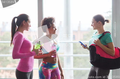 Image of happy women with bottles of water in gym