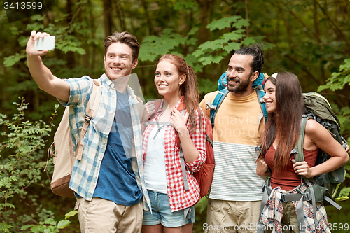 Image of friends with backpack taking selfie by smartphone