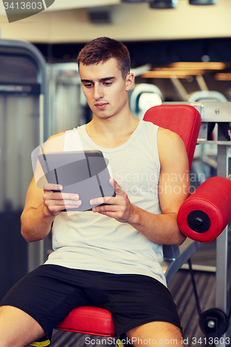 Image of young man with tablet pc computer in gym