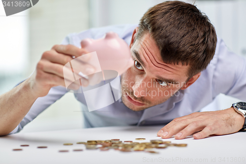 Image of businessman with piggy bank and coins at office