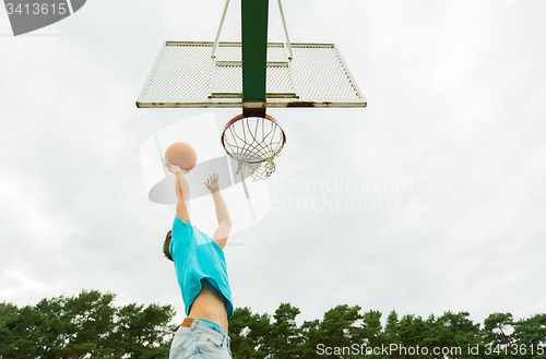 Image of young man playing basketball outdoors